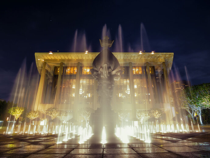 Water Shooting in the Air from Fountains at Night Outside Beautiful Building with Lights