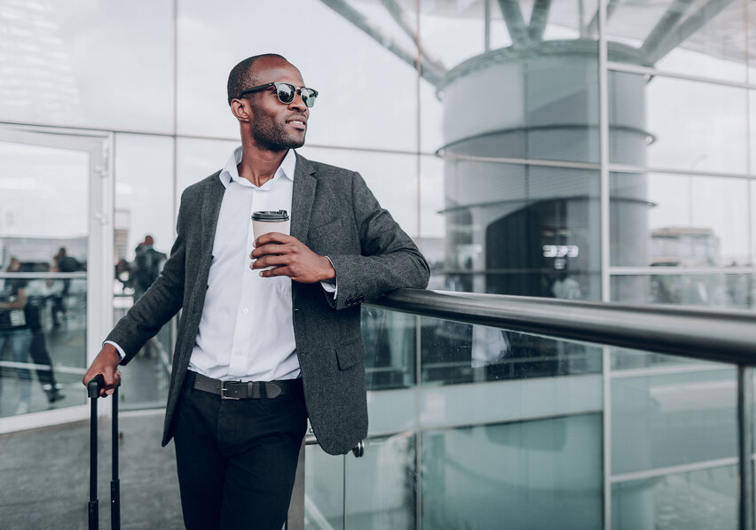 Man Wearing Sunglasses and Standing Next to Suitcase Looking Into the Distance