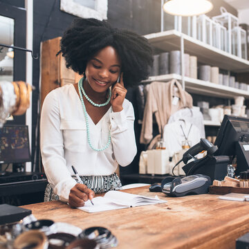 Woman Working in Store on the Phone, Writing Notes While at Front Desk