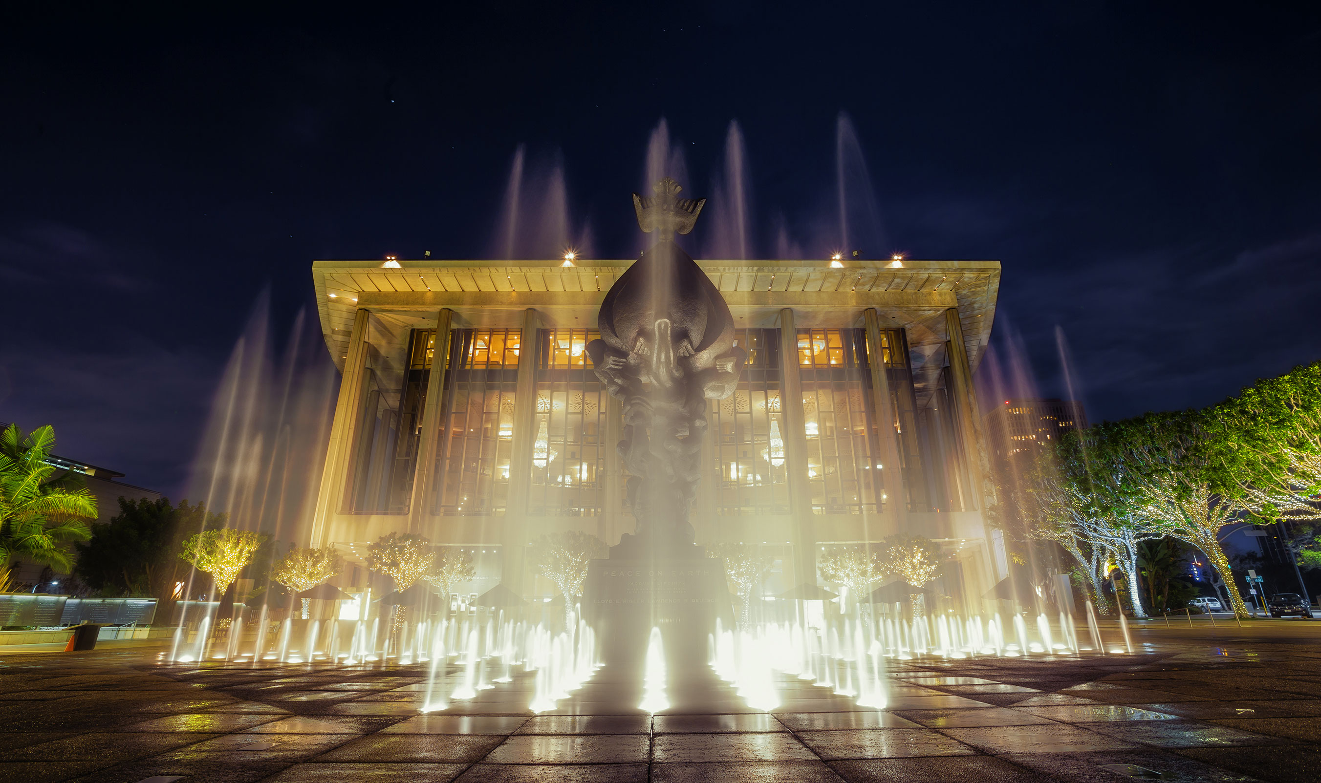 Water Shooting in the Air from Fountains at Night Outside Beautiful Building with Lights