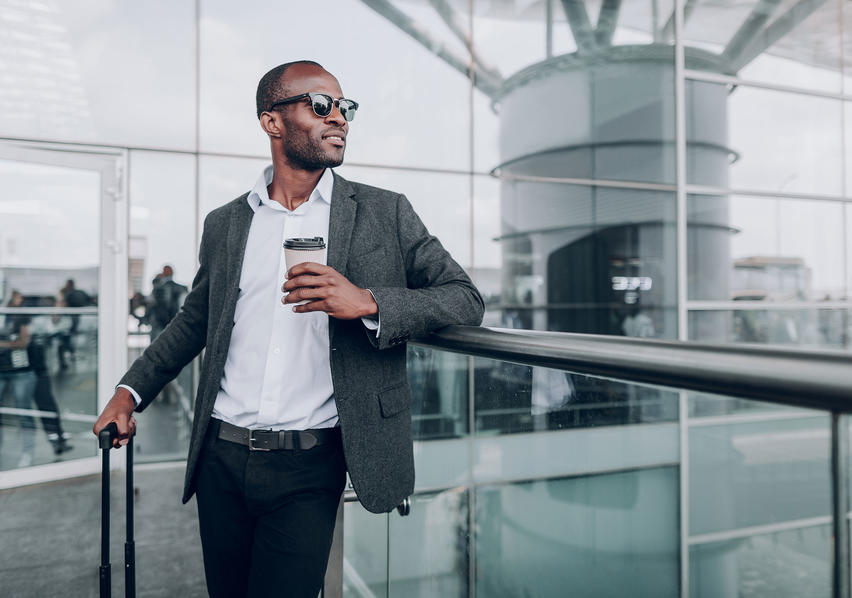Man Wearing Sunglasses and Standing Next to Suitcase Looking Into the Distance